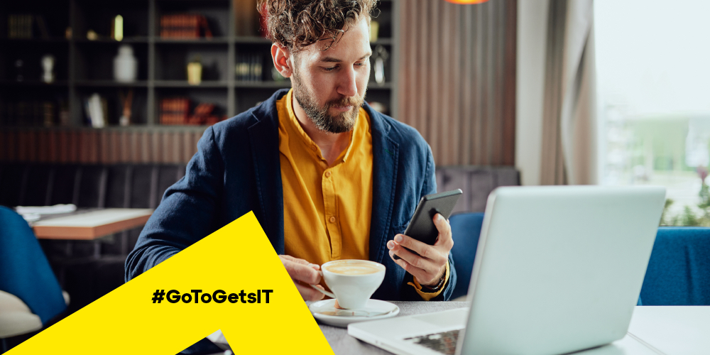 Man working from a café with a laptop and smartphone using authentication and authorization for secure IT