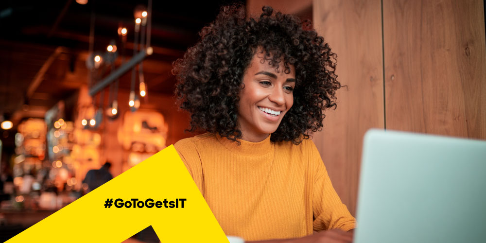 Femme qui télétravaille dans un café et est protégée contre les risques du travail à distance par les meilleures pratiques informatiques