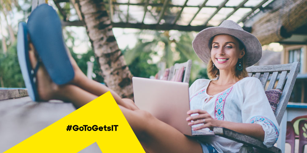 Woman working on a laptop with her feet in a tropical outdoor terrace setting, thanks to the principles of remote work as a technology