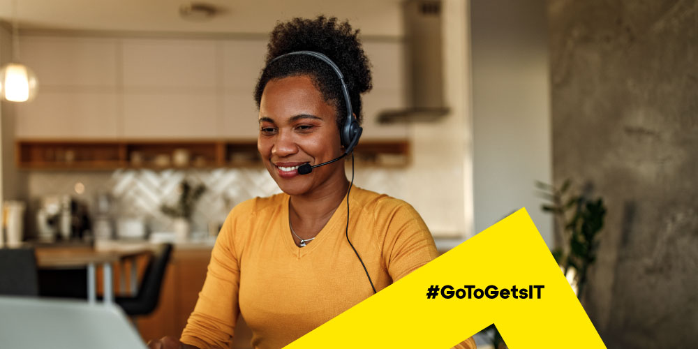 Woman wearing a headset and working on a laptop at home enabling PowerShell automation with zero trust security architecture