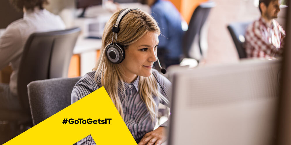 Agente de TI usando fones de ouvido e trabalhando em uma mesa com um software de emissão de alertas e monitoramento de servidor