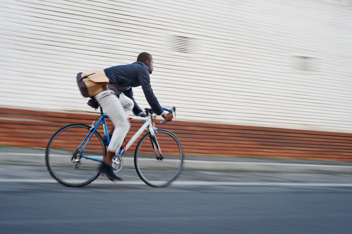 Young business man in casual work clothes riding bicycle, representing navigating economic uncertainty for SMBs and IT managers
