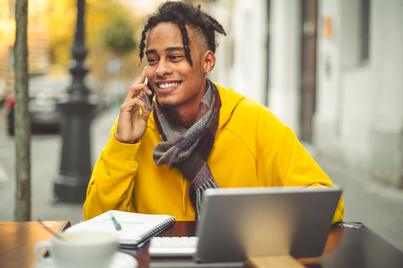 Young man working remotely at an outside café, thanks to IT teams managing and measuring the employee experience with IT support KPIs