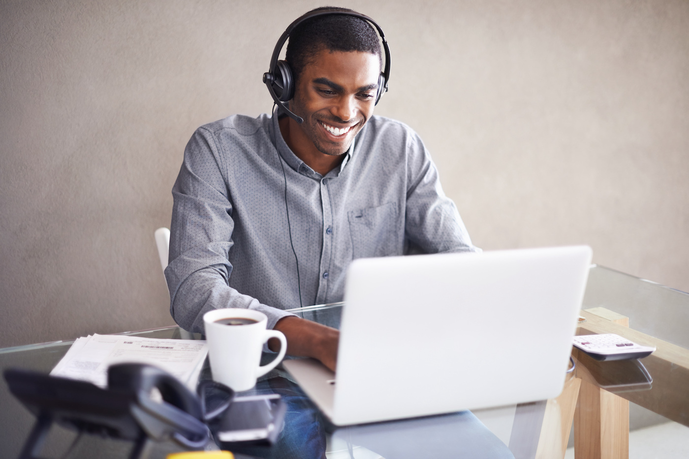 Man at a laptop in his remote workstation happily using GoTo Resolveās new RMM features: alerting, Windows patch management, and antivirus management for SMBs and MSPs