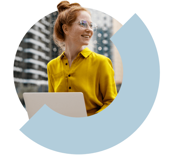 A woman smiling and working outside on her laptop.