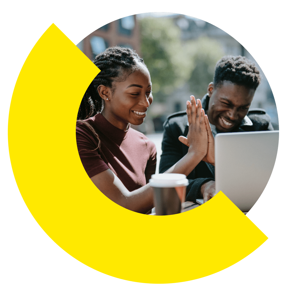 Duas pessoas sentadas ao ar livre e se cumprimentando na frente de um notebook.