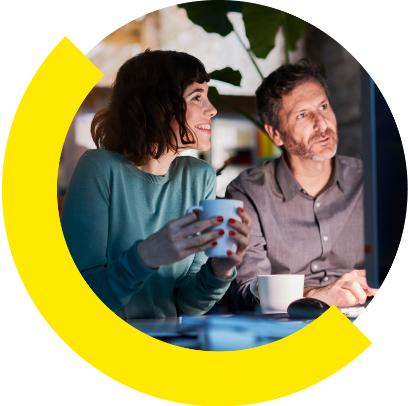 Duas pessoas sorrindo e olhando juntas para um computador.