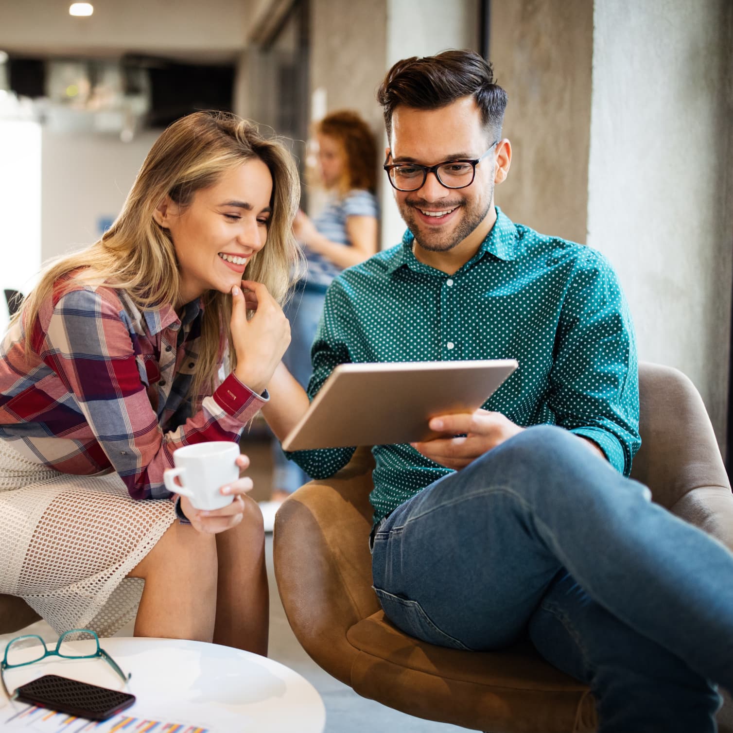 Collègues dans un bureau qui travaillent de manière sécurisée sur une tablette avec le mobile device manager de GoTo Resolve.
